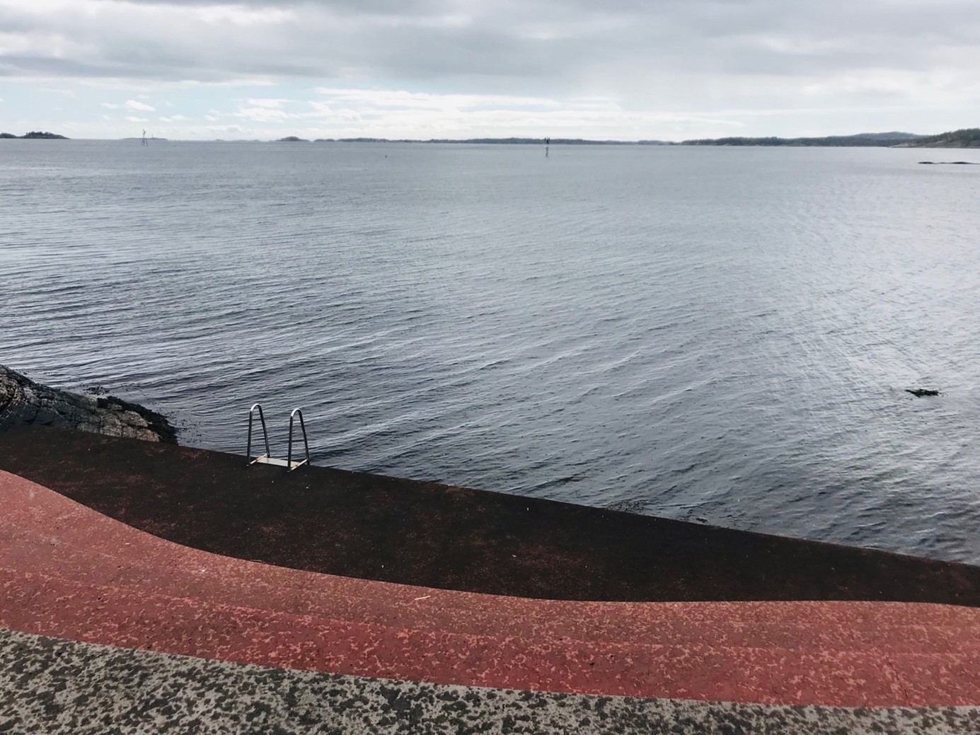 Et foto som inneholder himmel, hav, strand og en badetrapp. Foto: Lisbet Skregelid.