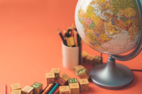 A globe with letter cubes and pencils around. Photo by Alexandr Podvalny on Unsplash