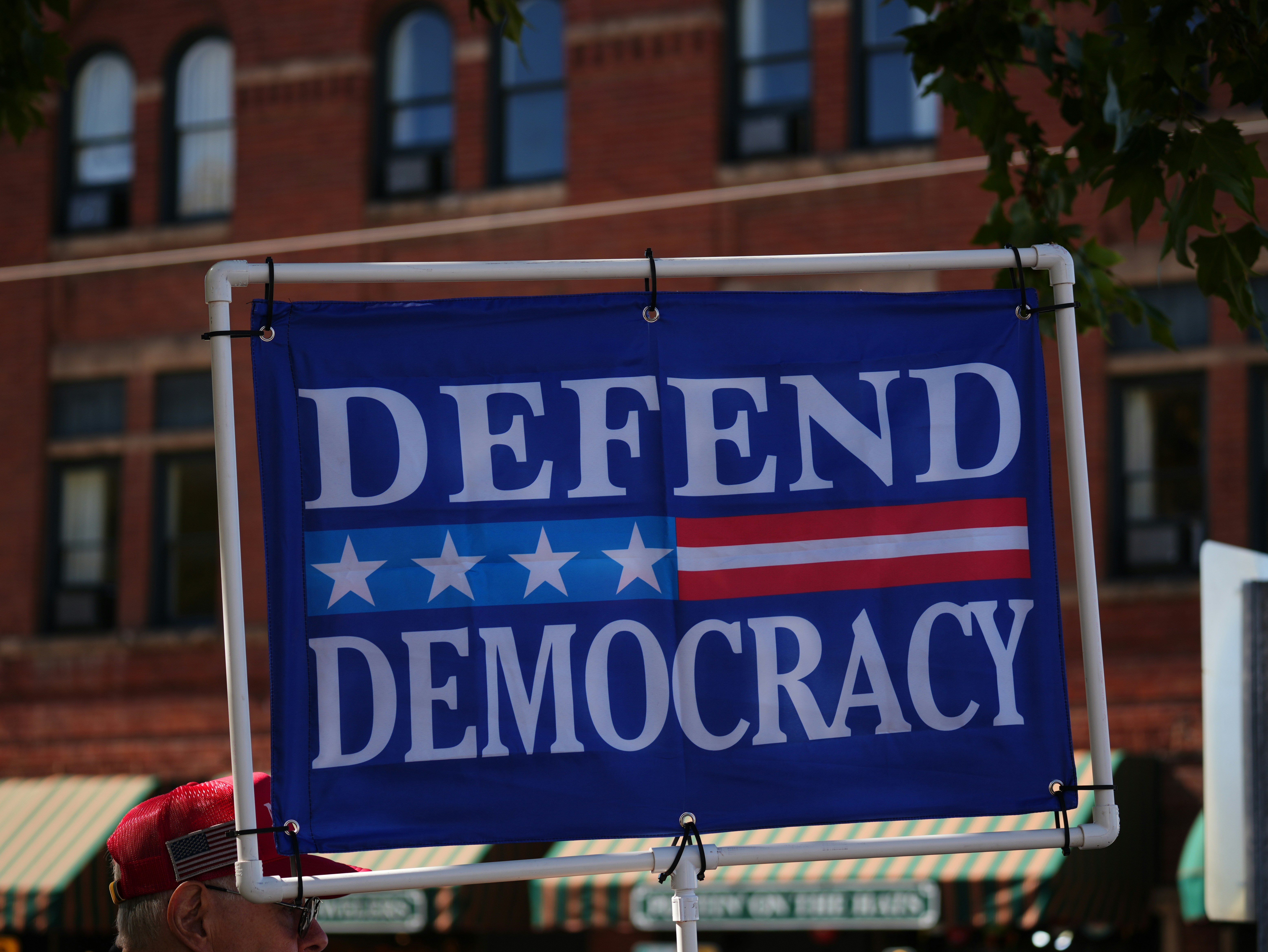 A flag with "Defend Democracy" including elements from the American flag. Photo by Donald Teel on Unsplash.  