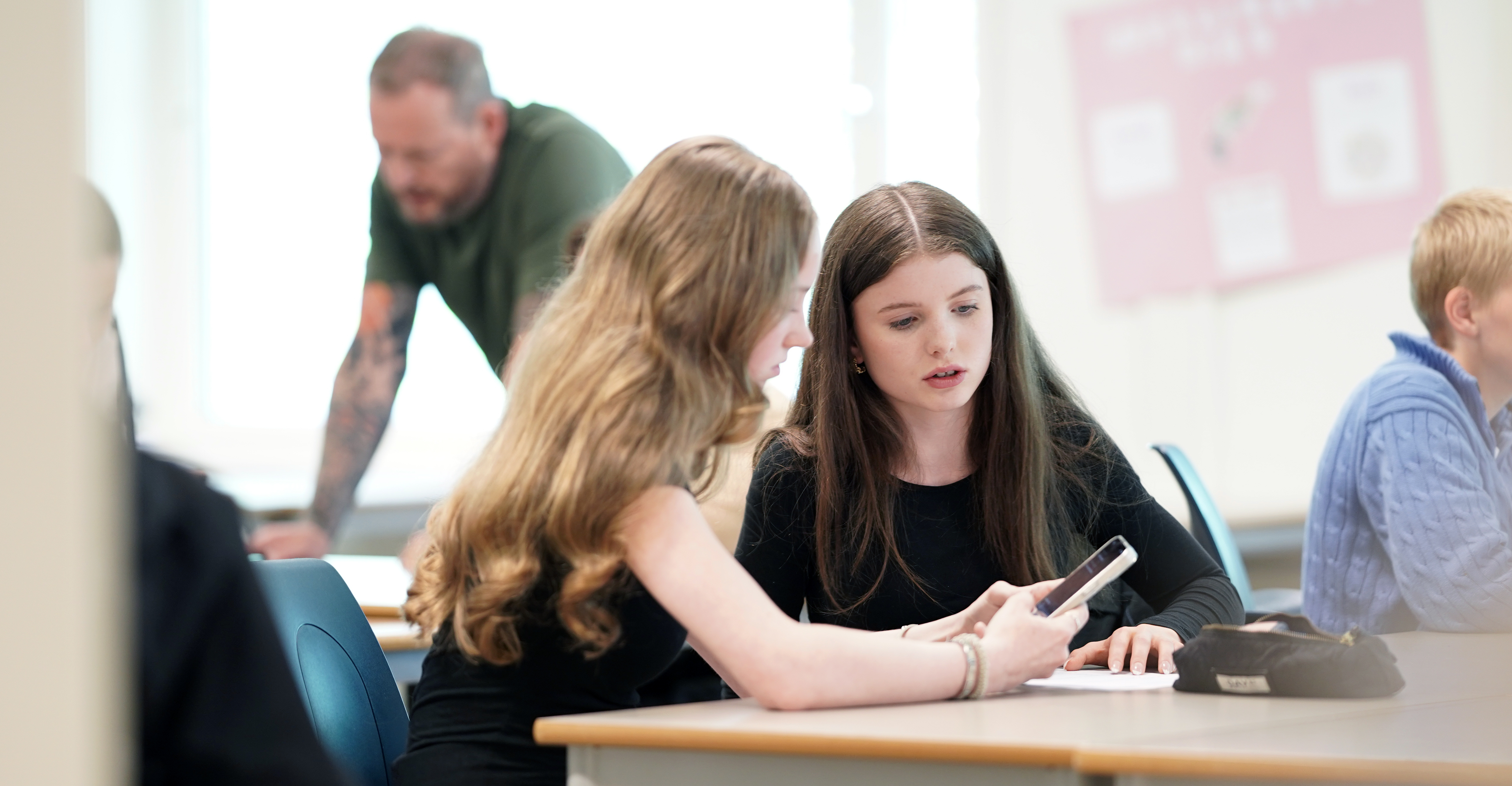 Two students in a classroom with a teacher in the backgroun. Credit: UiO/Shane Colvin