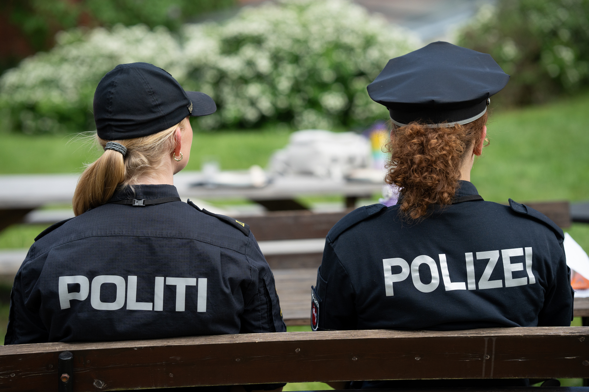 Two police officers sitting on a bench, one from Norway, the other from Germany