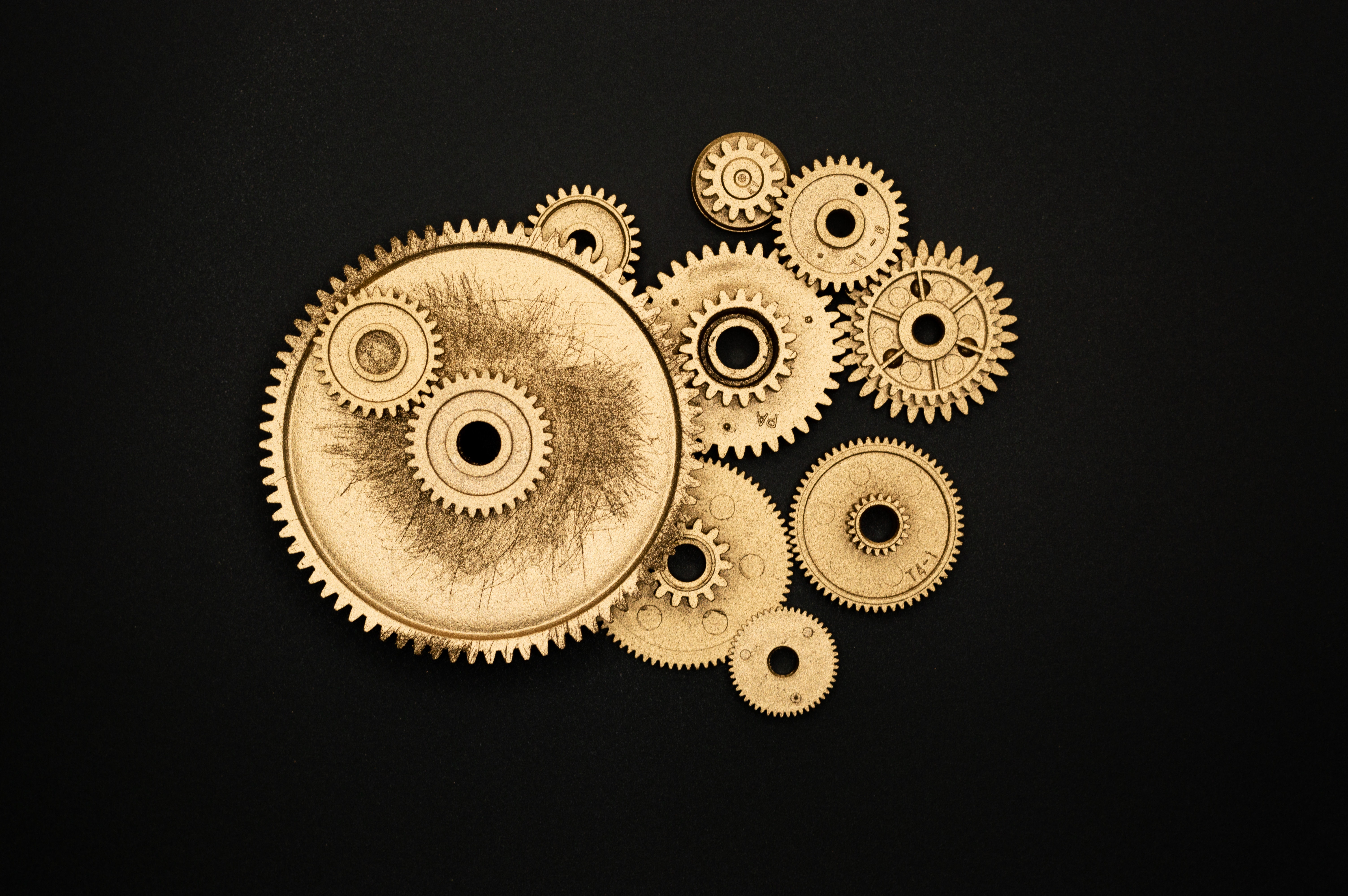 Golden gears on black background. Picture by Miguel Á. Padriñán from Pexels