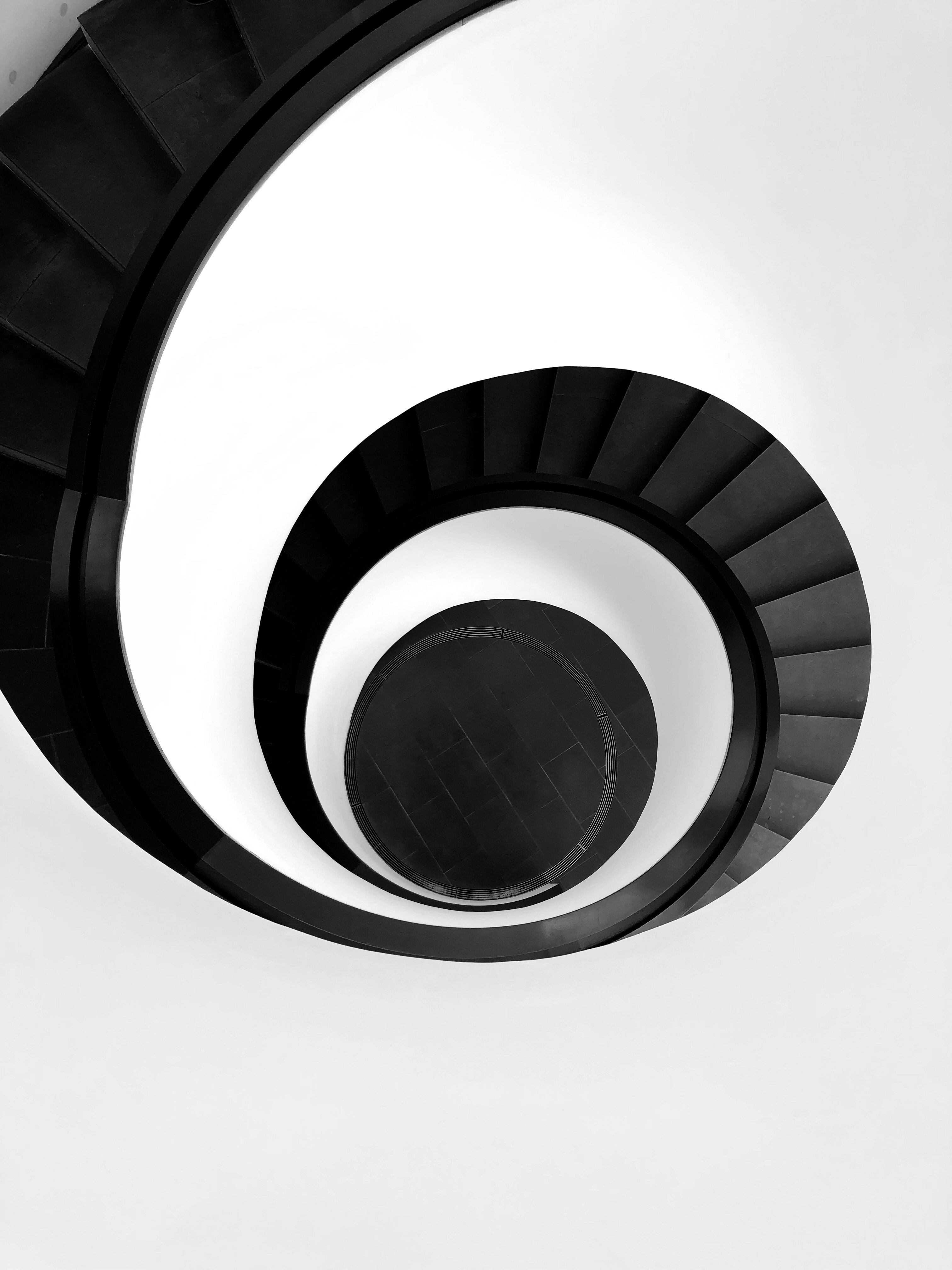 Spiral staircase with black steps and white walls, viewed from above. Picture by Robin Schreiner from Pexels.com